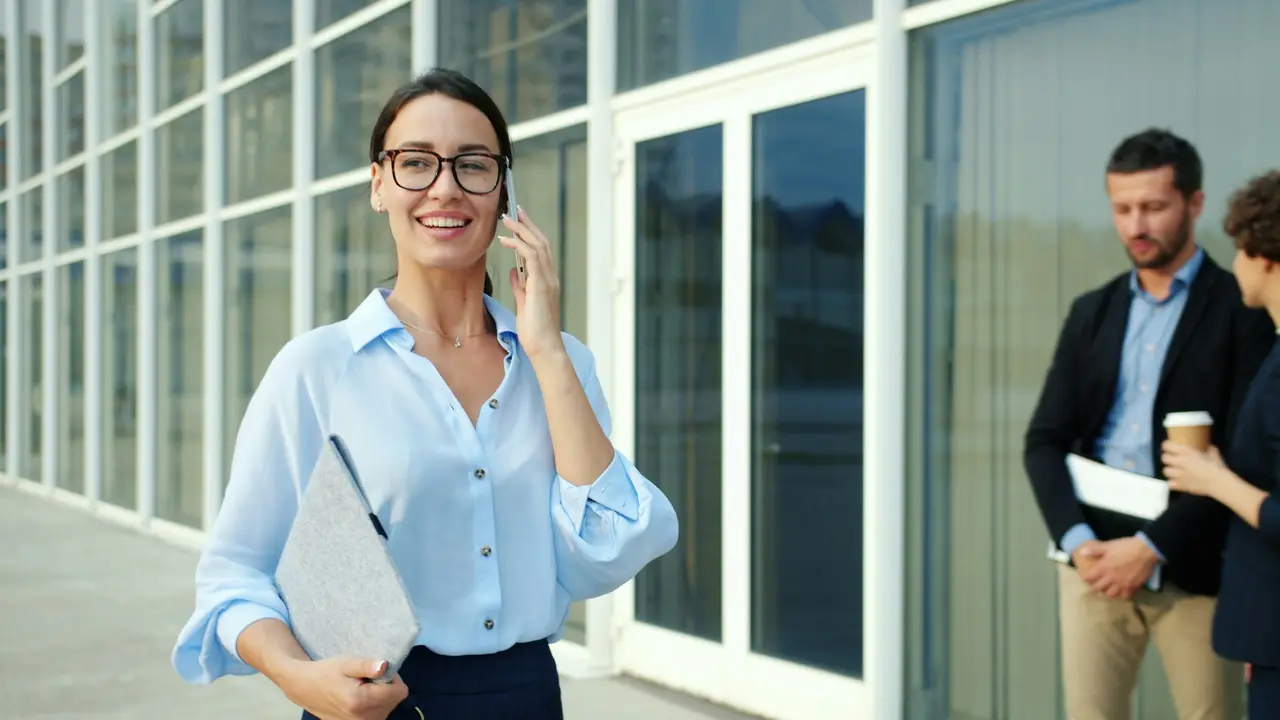 A professional woman on a phone call outside a modern office building