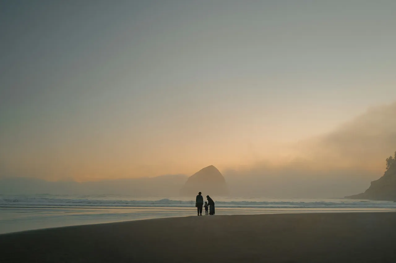 A family walking together on a misty beach at sunset