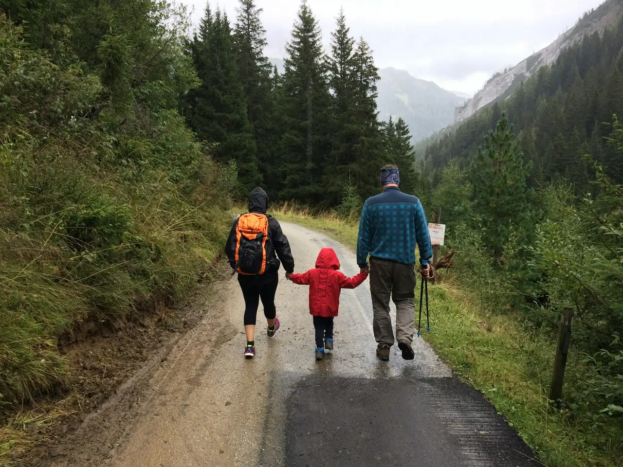 Two adults and a child walking together along a forest trail
