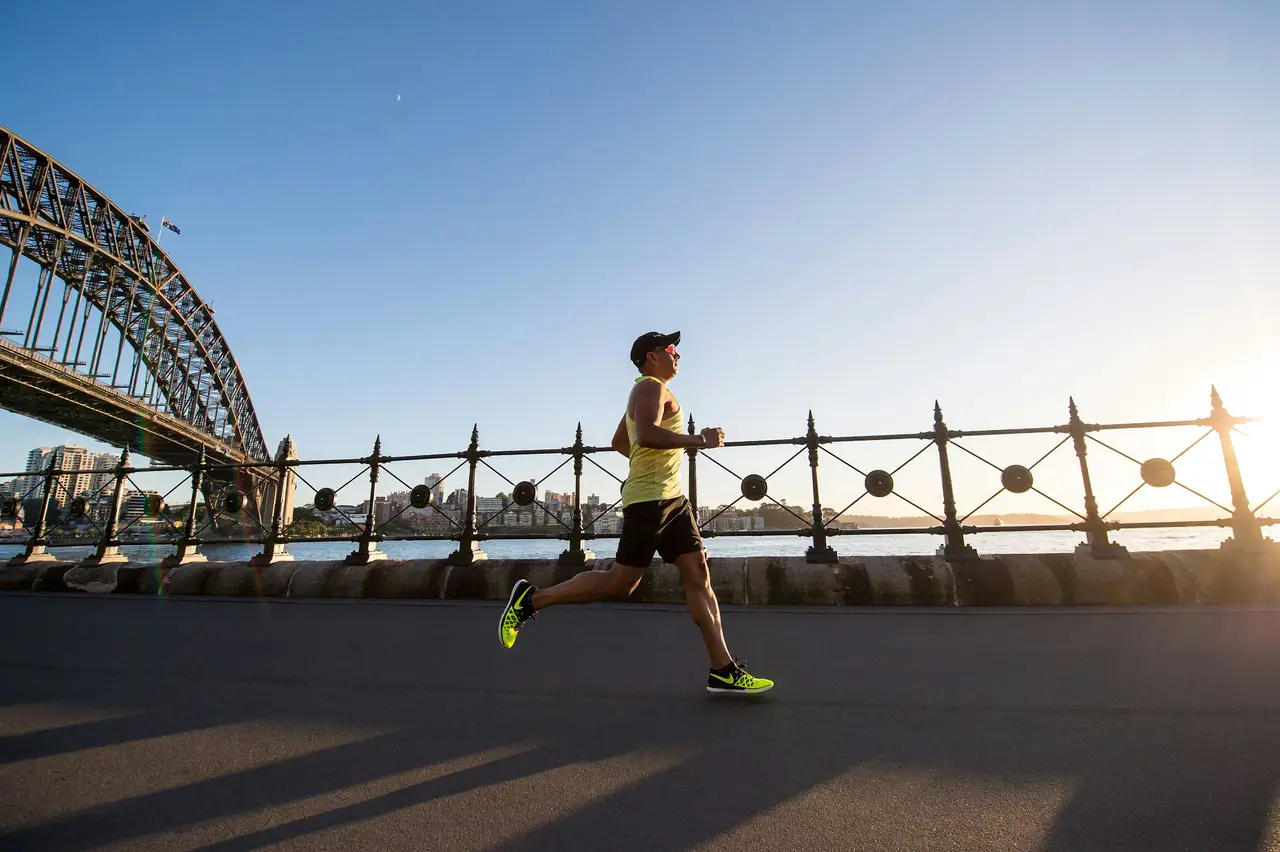 A man running along the harbour in the morning sun