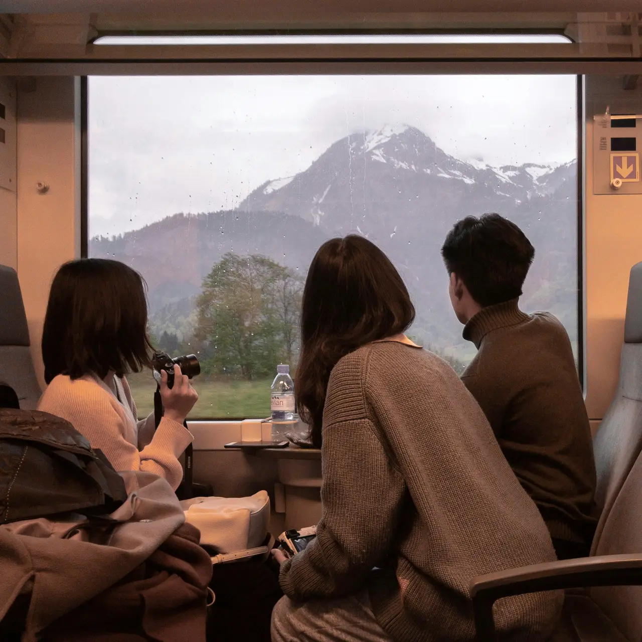 Travellers on a train looking out at snow-capped mountains