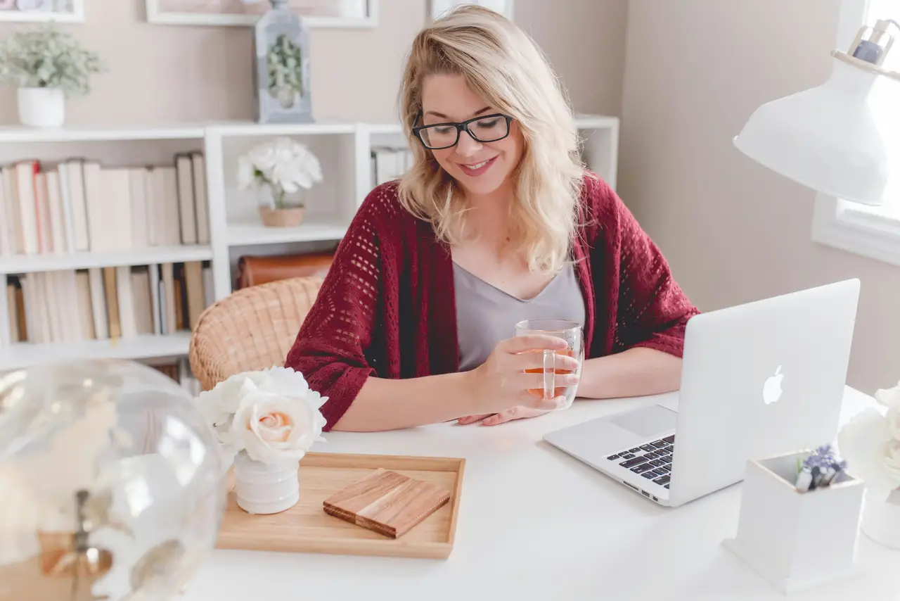 A woman smiling at her laptop during a video call at a bright desk